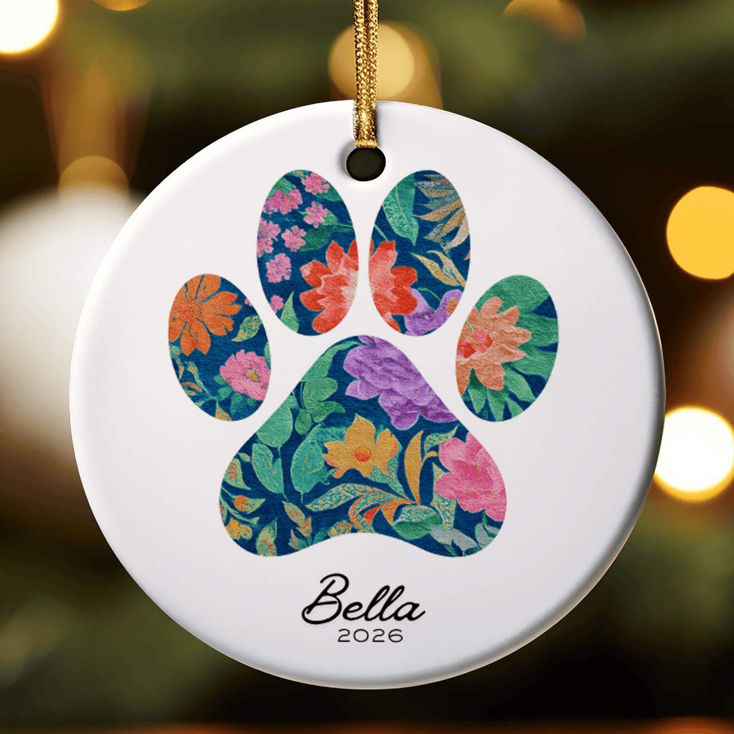 Decorative ornament with floral paw print design and 'Bella 2026' text on a blurred background.