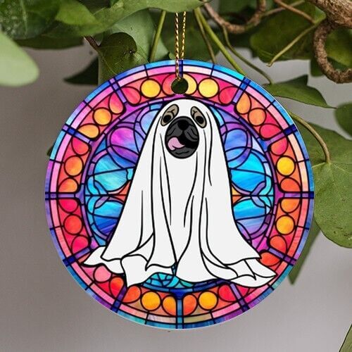 This halloween holiday ornament is in a stained glass art style. A ghost puppy floats in the middle smiling happily with his pink tongue popping out of his mouth in joy.