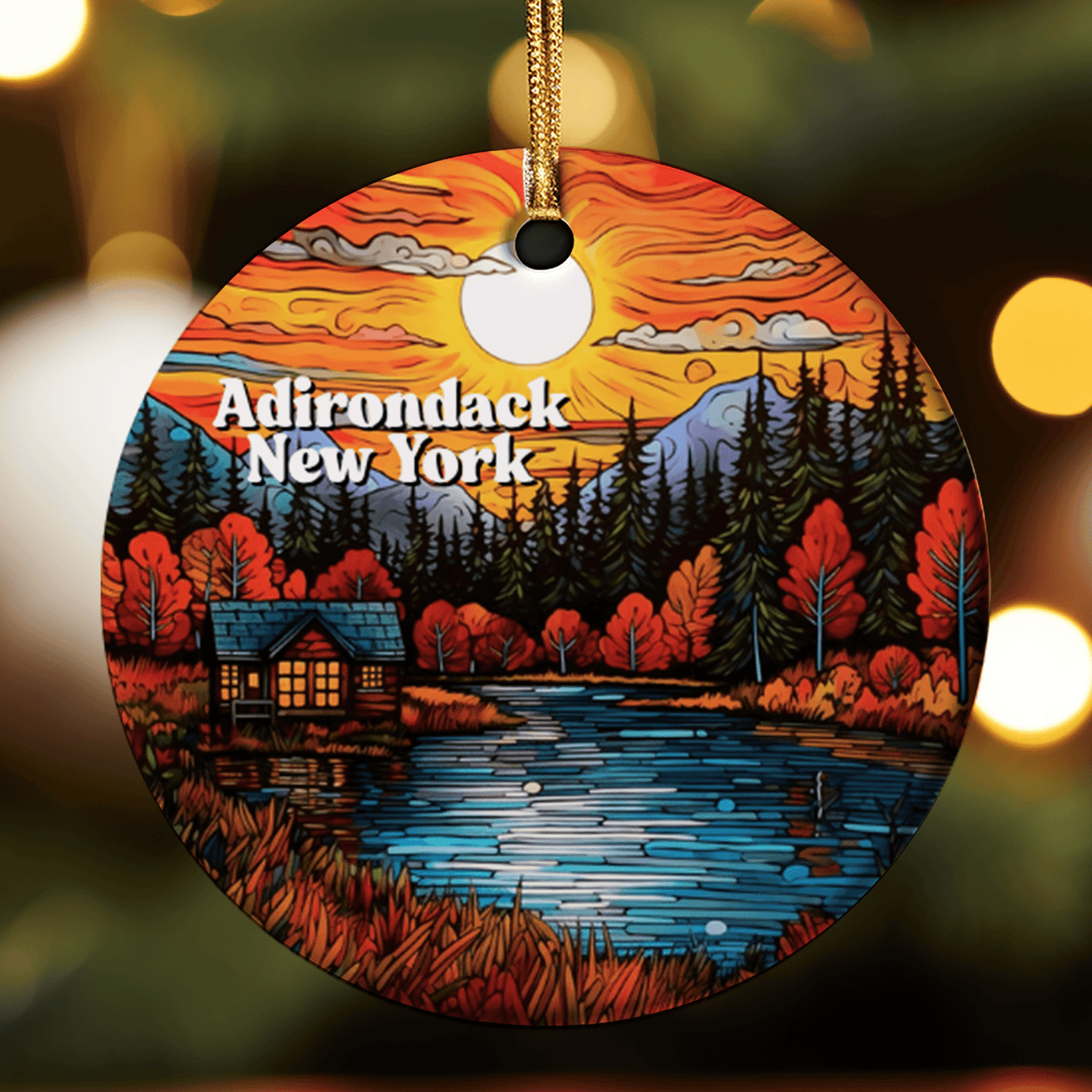 Round ornament with Adirondack New York design featuring a sunset over a lake and cabin.