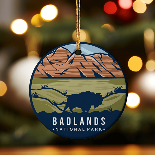 Holiday ornament featuring an image of Badlands National Park, showcasing a bison grazing on grass with rugged mountains in the background, capturing the park's unique landscape.