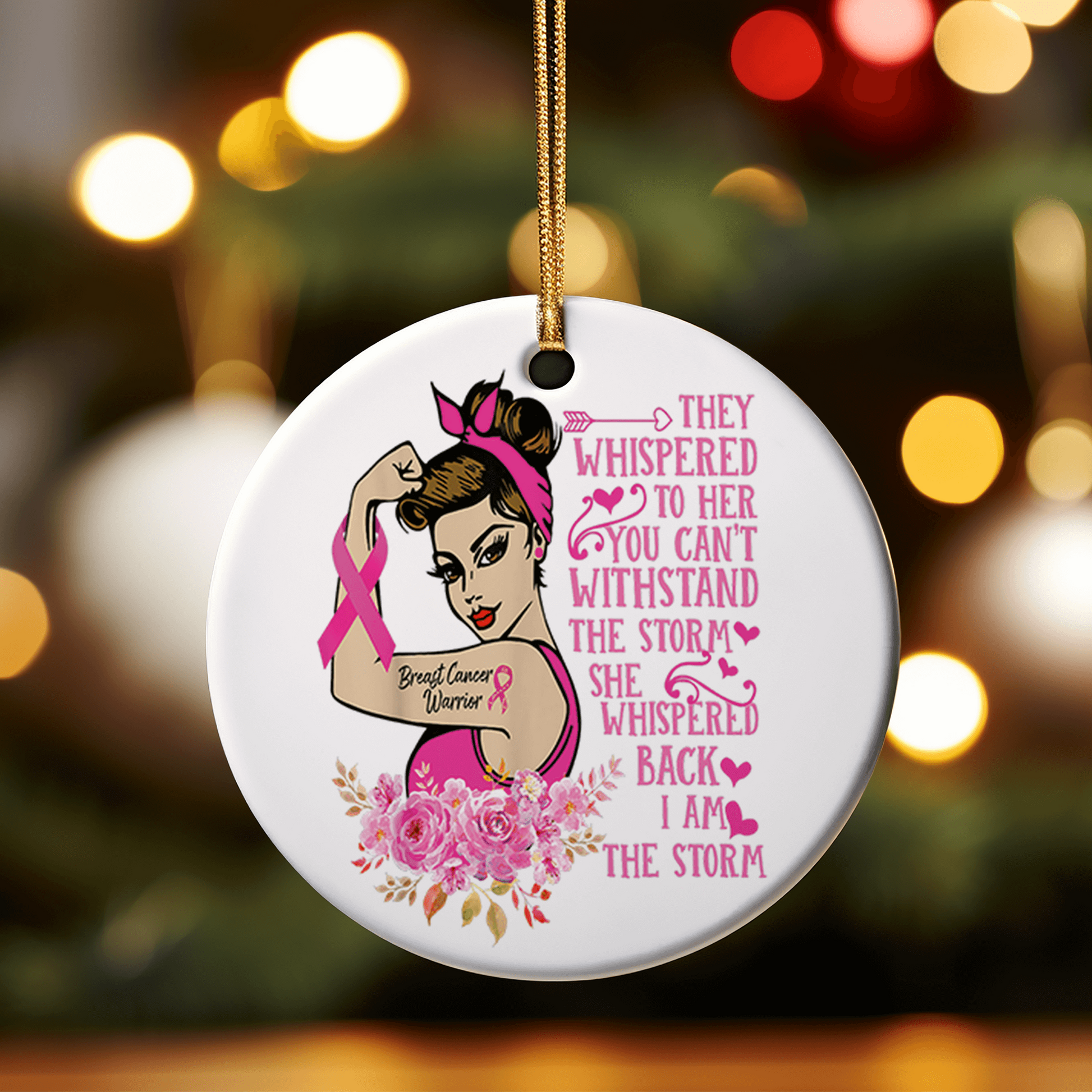 This holiday ornament  shows a fair skinned woman flexing a muscle with a Breast Cancer Warrior tattoo on the bicep. With text to the right stating She whispered back I am the Storm.