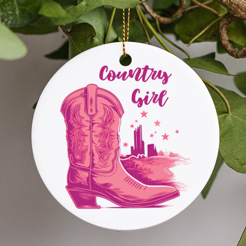 This Everyday Ornament is a painting with a cowgirl riding boot with winged designs etched into the side of the boot. A picturesque setting of the desert is the background horizon with nine stars in the sky all in different pink hues and tones.