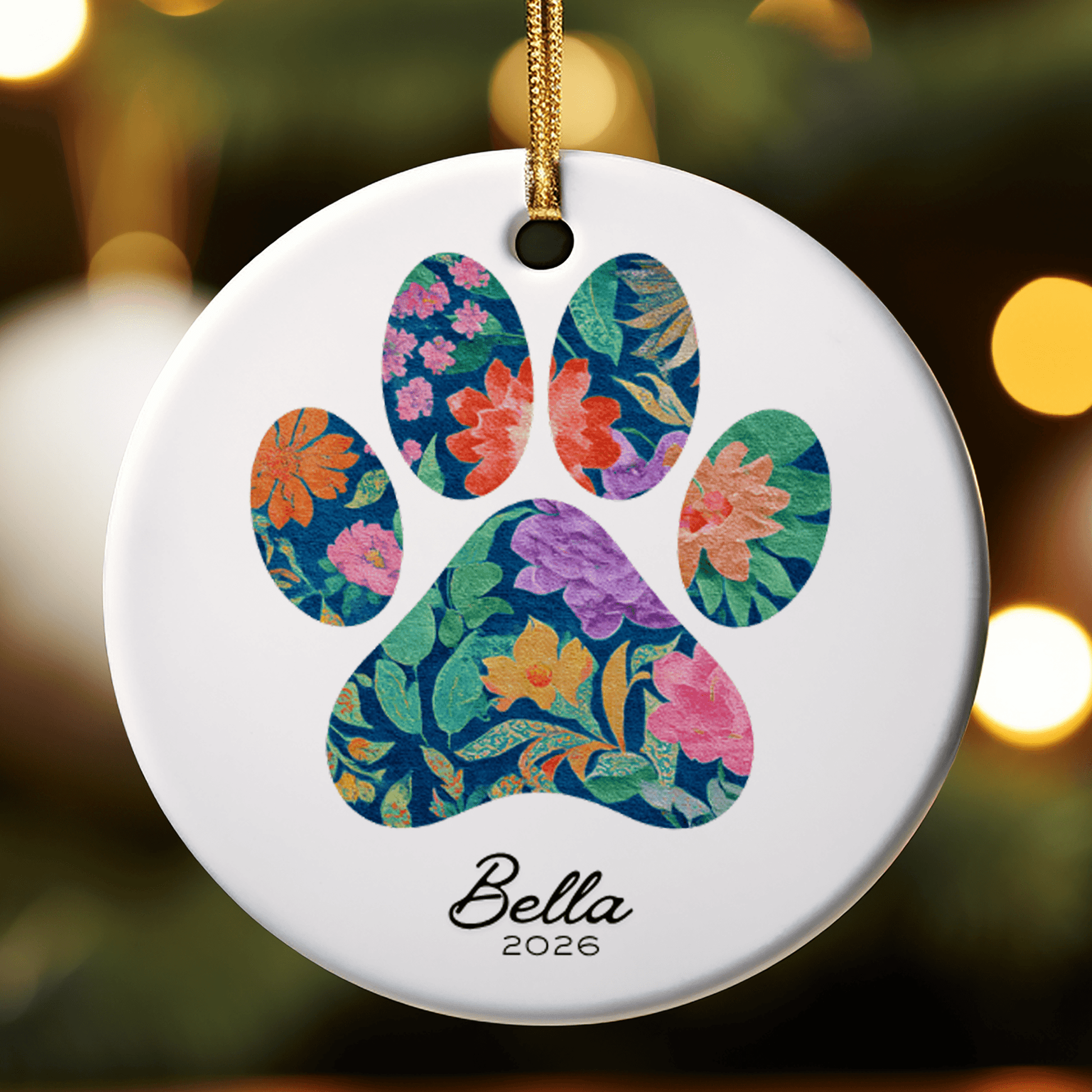 Decorative ornament with floral paw print design and 'Bella 2026' text on a blurred background.