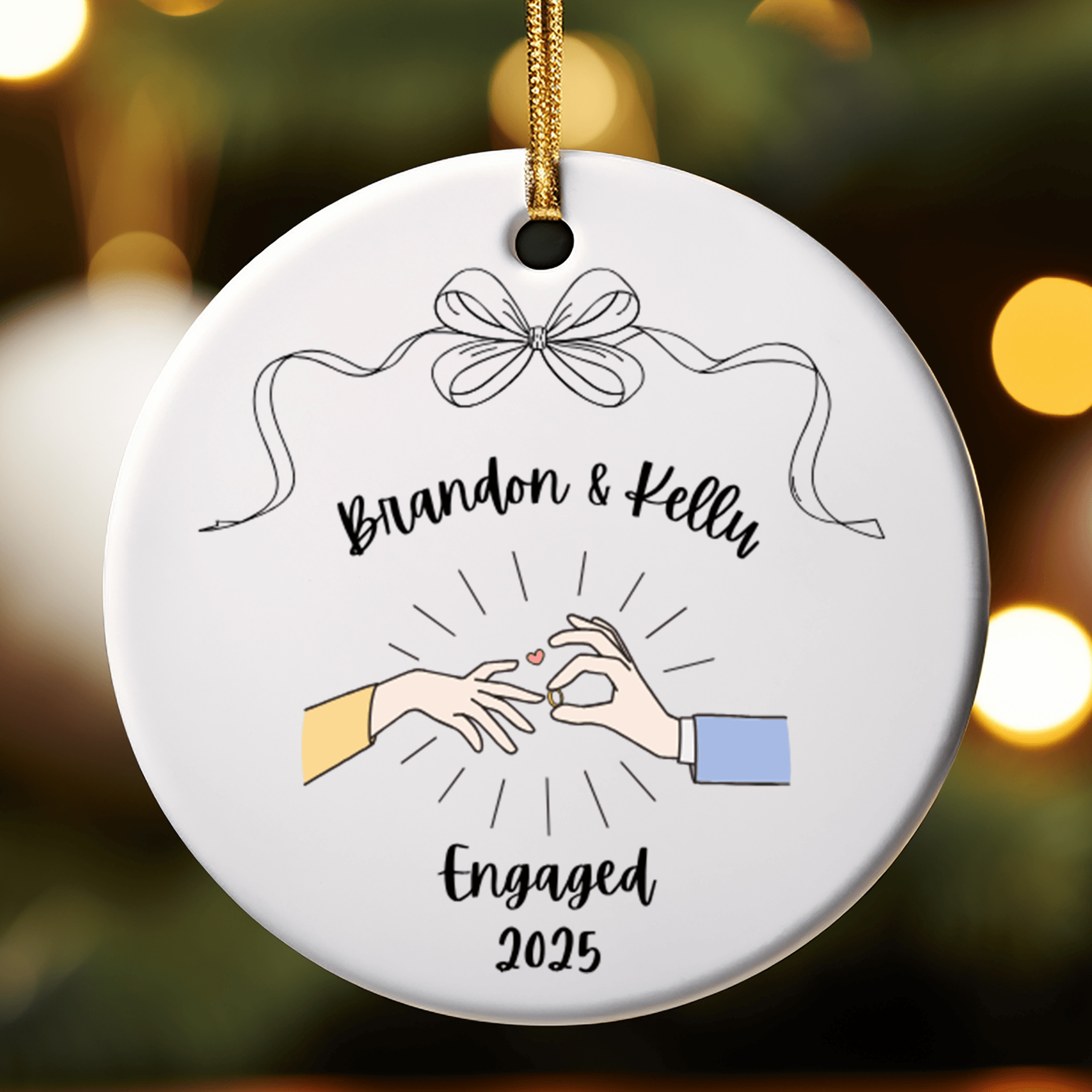 Decorative ornament with hands holding a heart and text 'Brandon & Kelly Engaged 2025' against a blurred festive background.