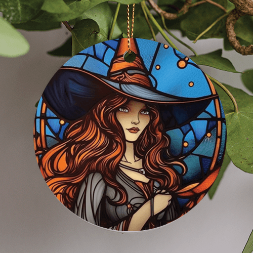 This halloween holiday ornament is in an illustration art style. The witch sits sideways looking out of the corner of her eyes wearing a light charcoal wide brimmed hat with copper accents to match her long flowing hair. Her gown is a solid light charcoal gray. Behind her is a blue paned glass window with orange circular frames.