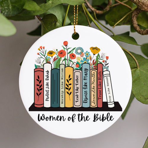 This Everyday Ornament is cartoon illustration of books stacked on a shelf. Various spring flowers sit behind as the background ten books in total of various pastel reds, blues, and yellows. Just below it reads - Women of the Bible.